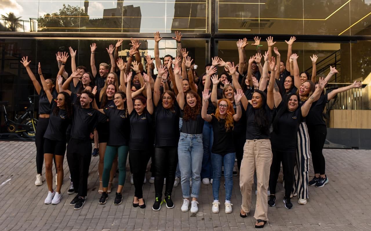 Equipe comemorando, de braços para o alto, na inauguração da unidade Carlos Trein
